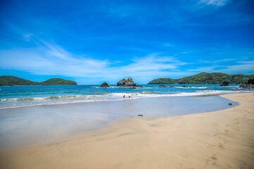 Sand beach among rocks on evening sunset. blue sky with a beautiful beach