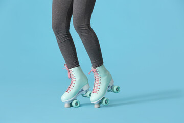 Sporty young woman on roller skates against color background