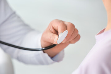 Pulmonologist with stethoscope examining patient in clinic, closeup