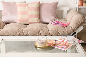 Candles, cosmetics and fashion magazine on table in room