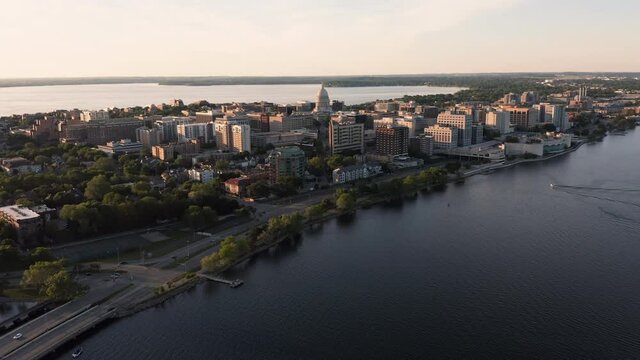 Flying above Lake Monona towards downtown of Madison with domed Wisconsin State Capitol on horizon, sunset light