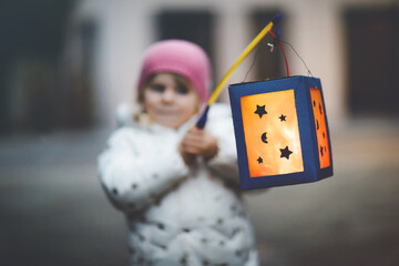 Close-up of little kid girl holding selfmade lanterns with candle for St. Martin procession....