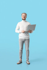 Young man with laptop on color background