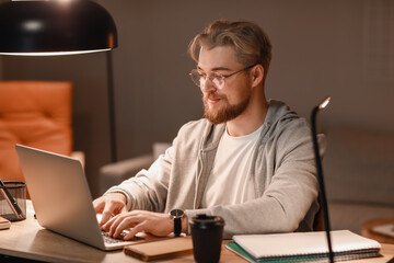 Young man studying online at home in evening
