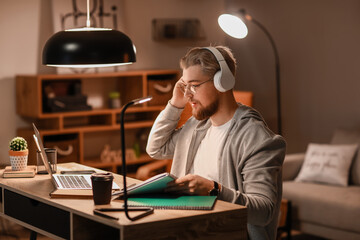 Young man studying online at home in evening