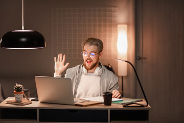 Young man studying online at home in evening