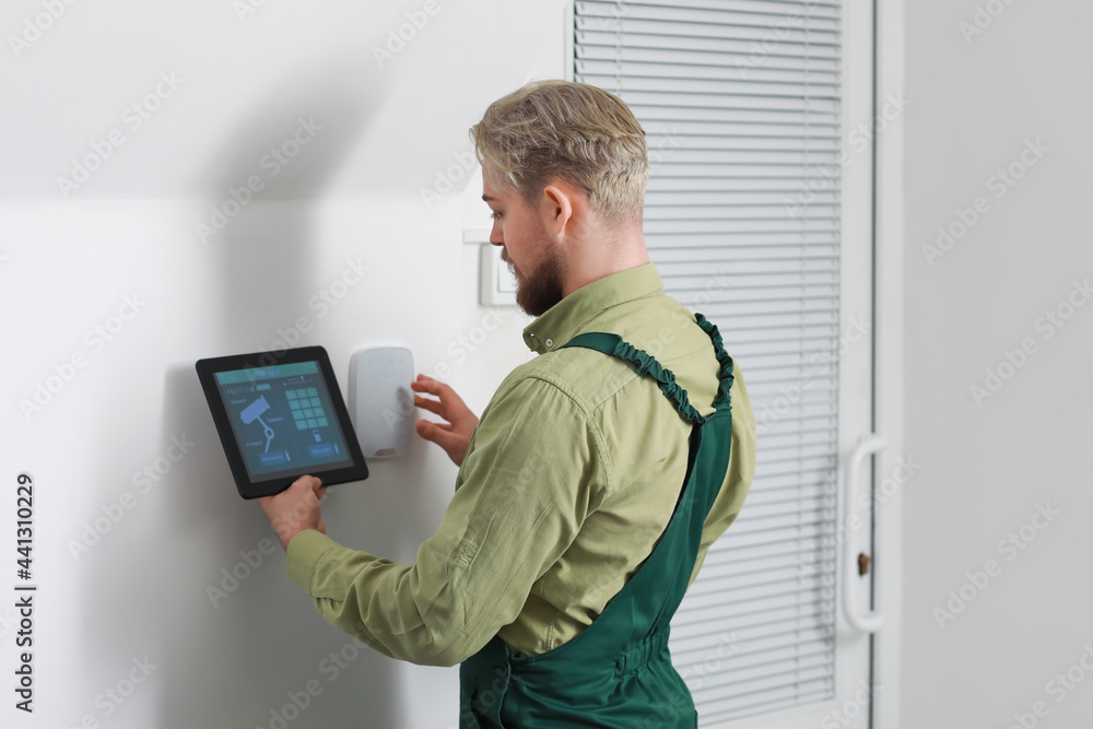 Poster worker with tablet computer checking alarm system indoors