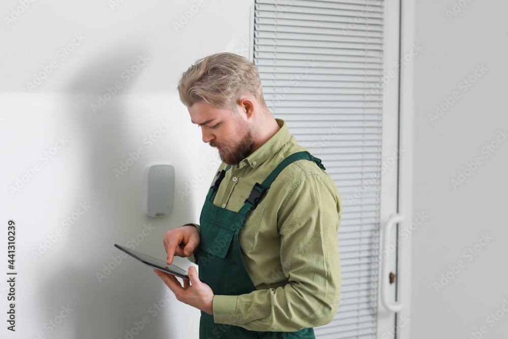 Poster worker with tablet computer checking alarm system indoors