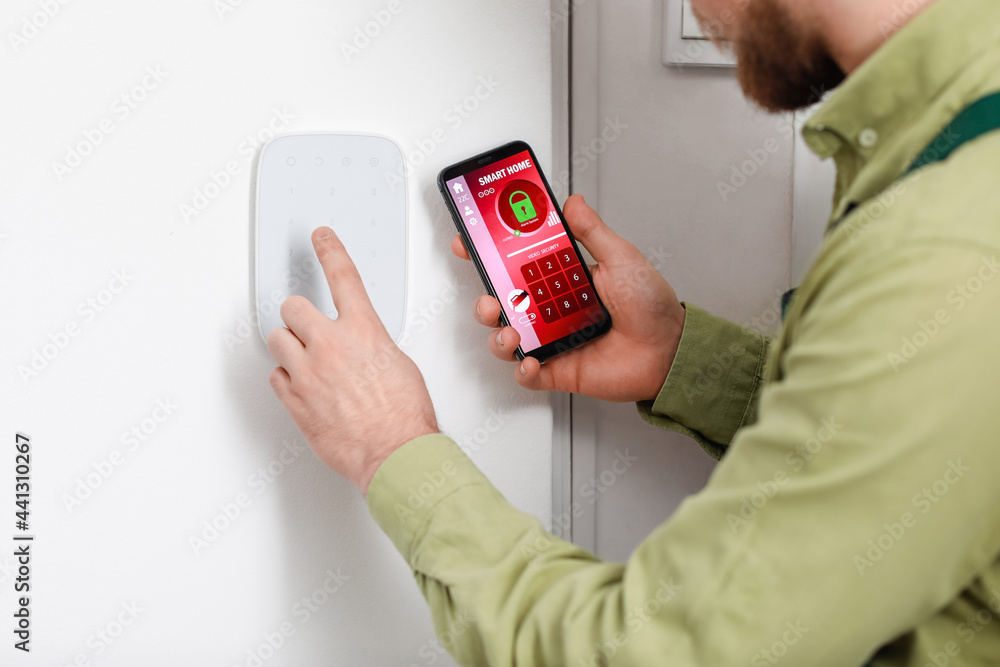 Poster worker with smartphone checking alarm system indoors