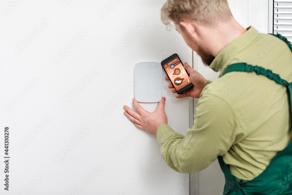 Poster worker with smartphone checking alarm system indoors