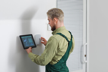 Worker with tablet computer checking alarm system indoors