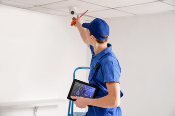 Worker installing alarm system indoors - obrazy, fototapety, plakaty