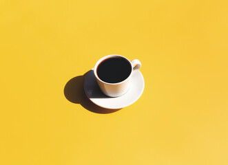 Cup and plate of coffee with shadow of sun on yellow beige terracotta background