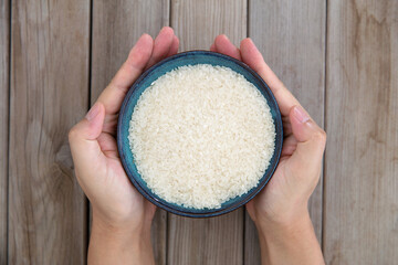 Hand holding a bowl of rice grain