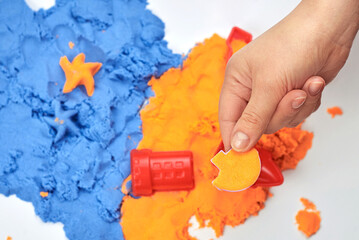 The girl's hand holds a sand beads filled with bright kinetic sand.