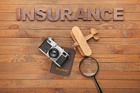 Composition with word INSURANCE and photo camera on wooden background