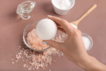 Female hand and homemade bath bomb on color background