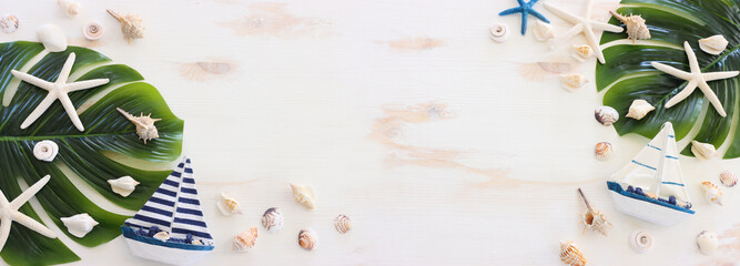 nautical concept with white decorative sail boat, seashells over white wooden background
