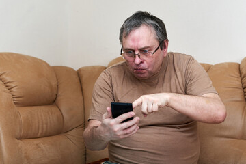Senior citizen sitting on the couch understands the gadget, mastering smartphone