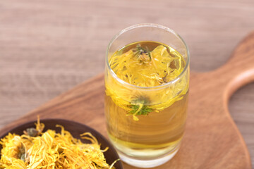 A plate of chrysanthemum and a cup of chrysanthemum tea on a cutting board