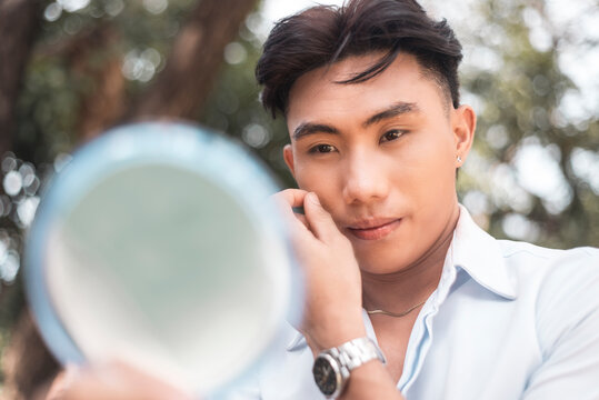 A vain young man checks his reflection in the mirror. Narcissistic behavior.