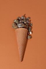 The concept of summer refreshment. Ice cream cone with sea pebbles. 