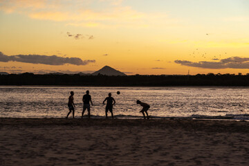 Silhouettes of People Playing Soccer on Beach at Sunset Time