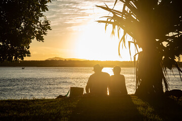 Silhouette of Couple Sitting on River Bank at Sunset Time in Noosa, Australia. Romantic Concept