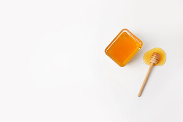 Glass bowl with sweet honey and dipper on white background
