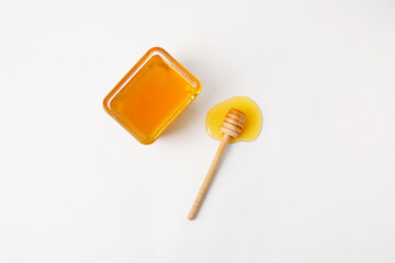 Glass bowl with sweet honey and dipper on white background