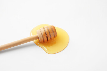 Wooden dipper and spilled honey on white background