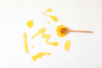 Fototapeta na wymiar Wooden dipper and spilled honey on white background