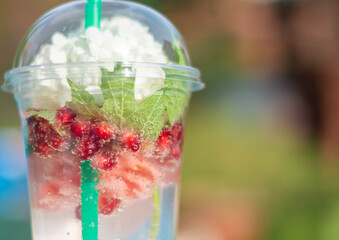 Cocktail with watermelon slices and ice in plastic cups with a flower. on a white background, on the edge of the resort pool. The concept of a luxury holiday. Outdoor pool background. Horizontal.
