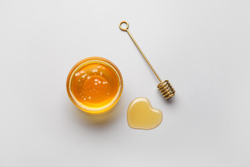 Heart made of honey and dipper on white background