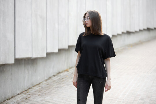 Woman or girl wearing black blank cotton t-shirt with space for your logo, mock up or design in casual urban style