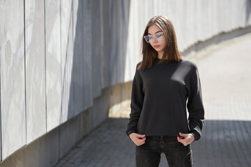 Woman wearing black sweatshirt or hoodie for mock up, logo designs or design prints with with free space on the city streets.