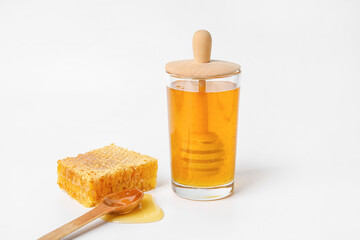 Glass with sweet honey, dipper and comb on white background