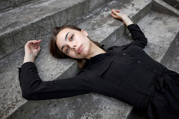 Fashion headshot of a sexy brunette woman with a make up wearing black dress in urban area