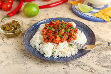 Plate with tasty chili con carne, rice and pickled jalapeno on color background
