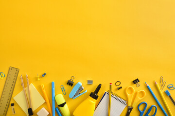 Row of yellow and blue school supplies on yellow top