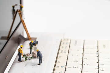 Miniature people working on upgrading and maintaining the laptop