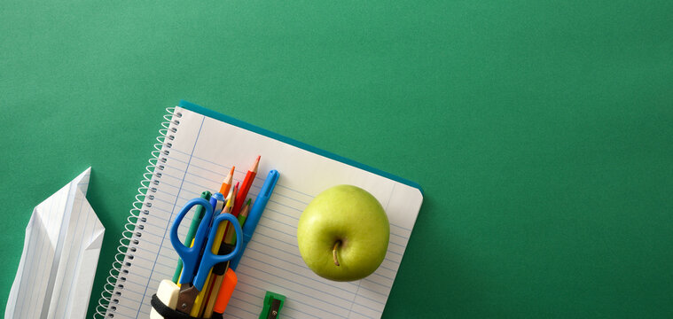 School tools with paper plane and apple on green panoramic