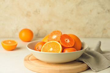 Plate with healthy oranges and tangerines on light background