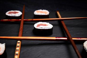 Three in a row made with sushi and chopsticks. Oriental food concept