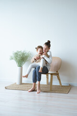 at home two sisters are sitting on a wooden chair playing playing laughing on a white background