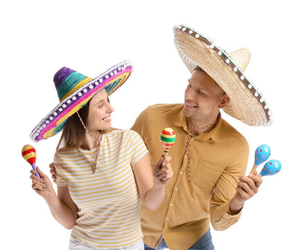 Happy young Mexican couple in sombrero hats and with maracas on white background