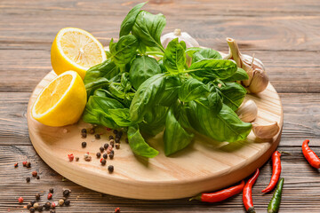 Fresh basil leaves, lemon and spices on wooden background
