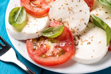 Piatto di insalata caprese fresca, piatto leggero tipico della cucina italiana con pomodoro fresco, mozzarella, basilico, olio extravergine di oliva e origano 