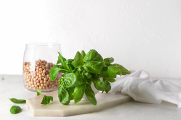 Bowl with fresh basil leaves and chickpea on light background