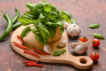 Composition with fresh basil leaves, garlic, tomatoes and chili peppers on grunge background